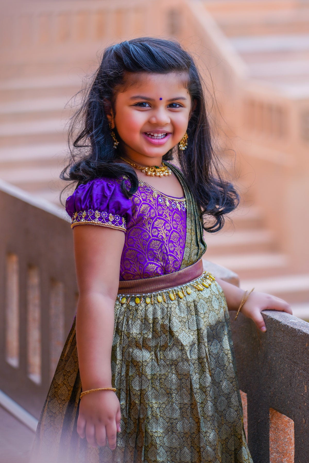 Smiling Baby Anika in purple pattu dress on steps