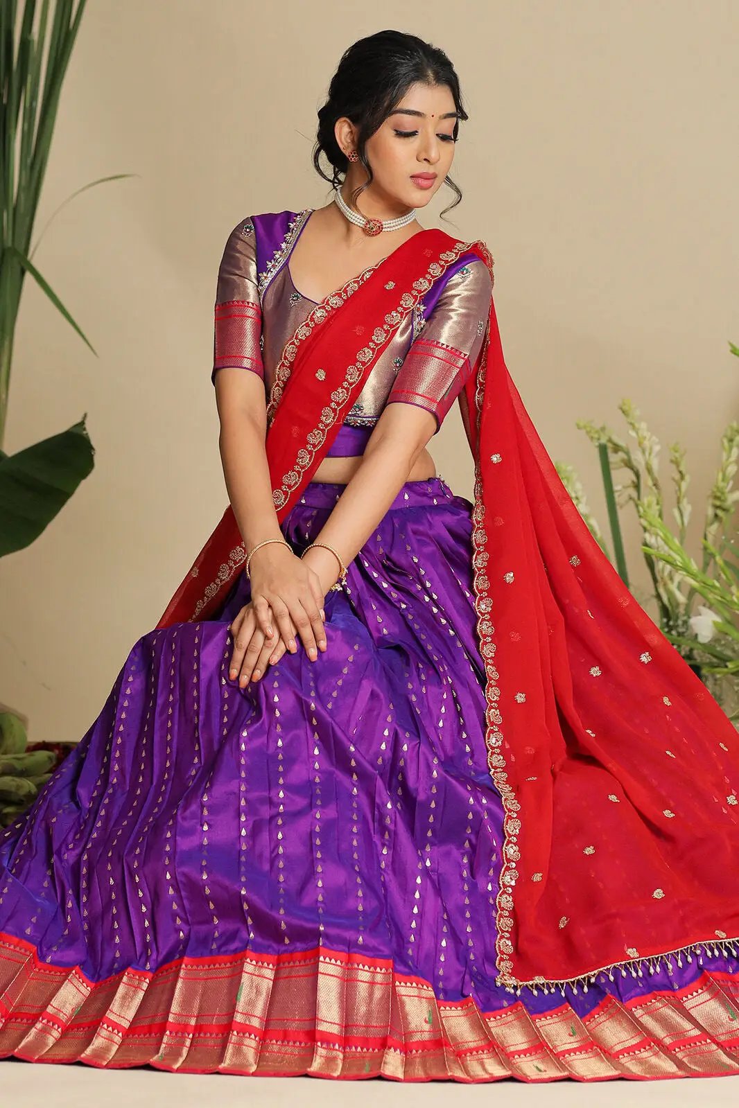 Elegant purple lehenga set with red dupatta, seated pose