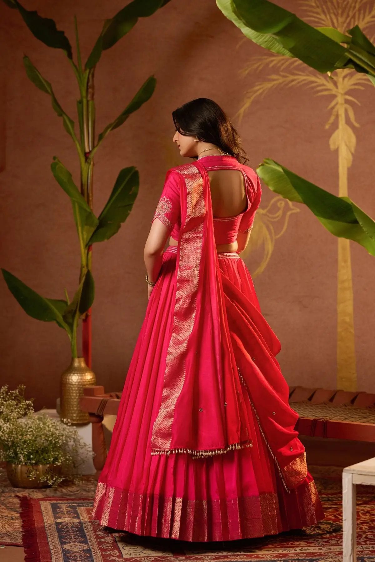 Back view of the Pritti Lehenga Set in Rani Pink, showcasing the stylish blouse cut and flowing dupatta with intricate border work.