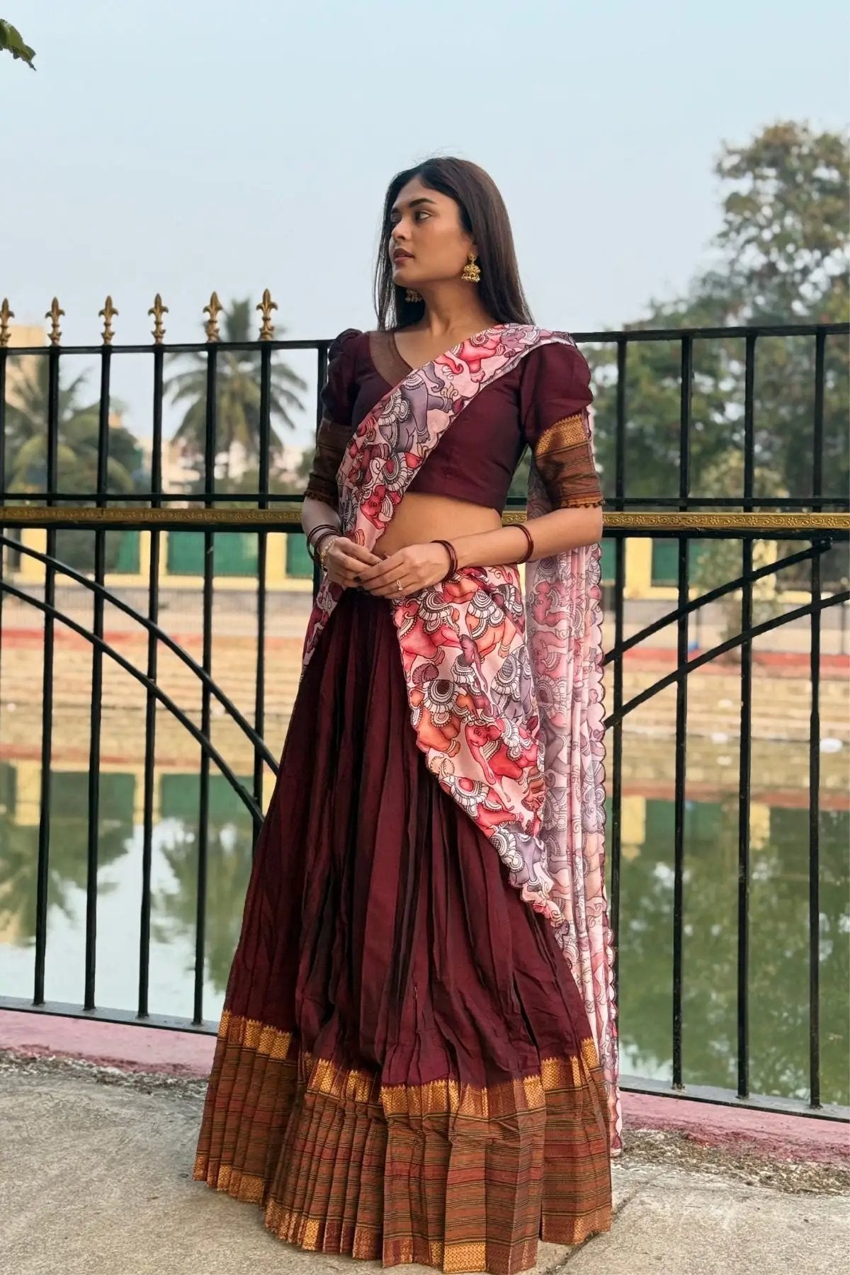 Full view of Saumya Handloom Lehenga Set in maroon featuring a pleated skirt, golden border, and vibrant floral dupatta.