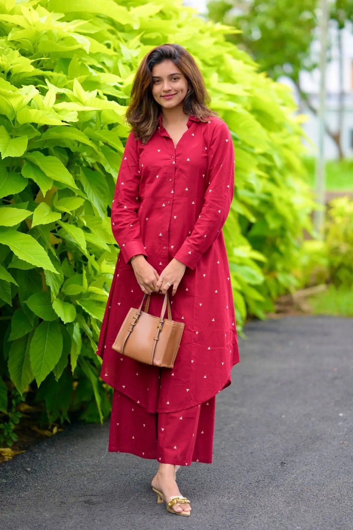 Woman holding a brown handbag in maroon kurta set