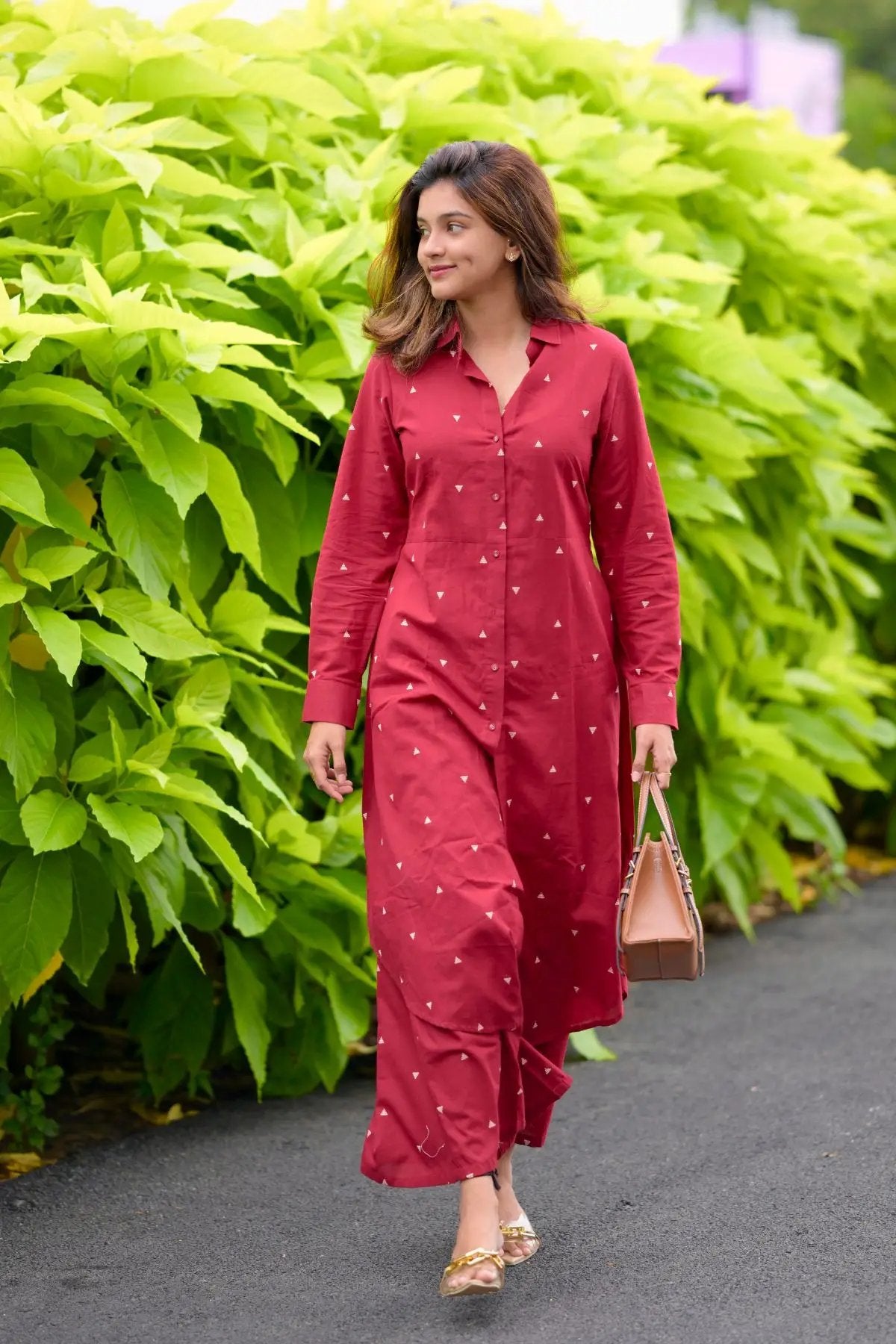 Woman in maroon kurta set walking on path