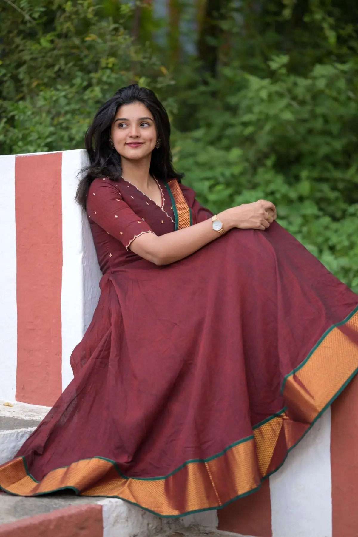 Woman seated in maroon dress with golden border