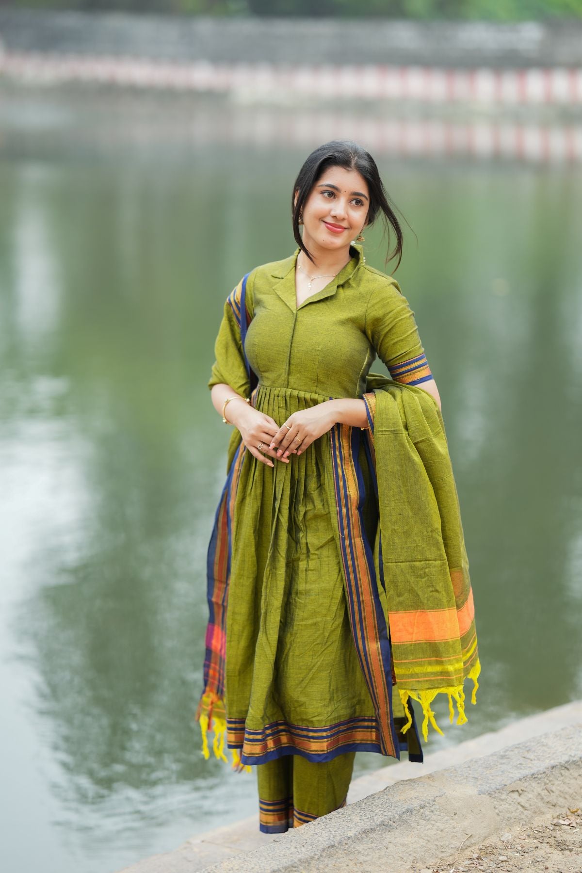 Graceful Syahi Handloom Suit Set in olive green, featuring a flared kurta and a vibrant dupatta with tassel details. Find this stylish set at bullionknot.