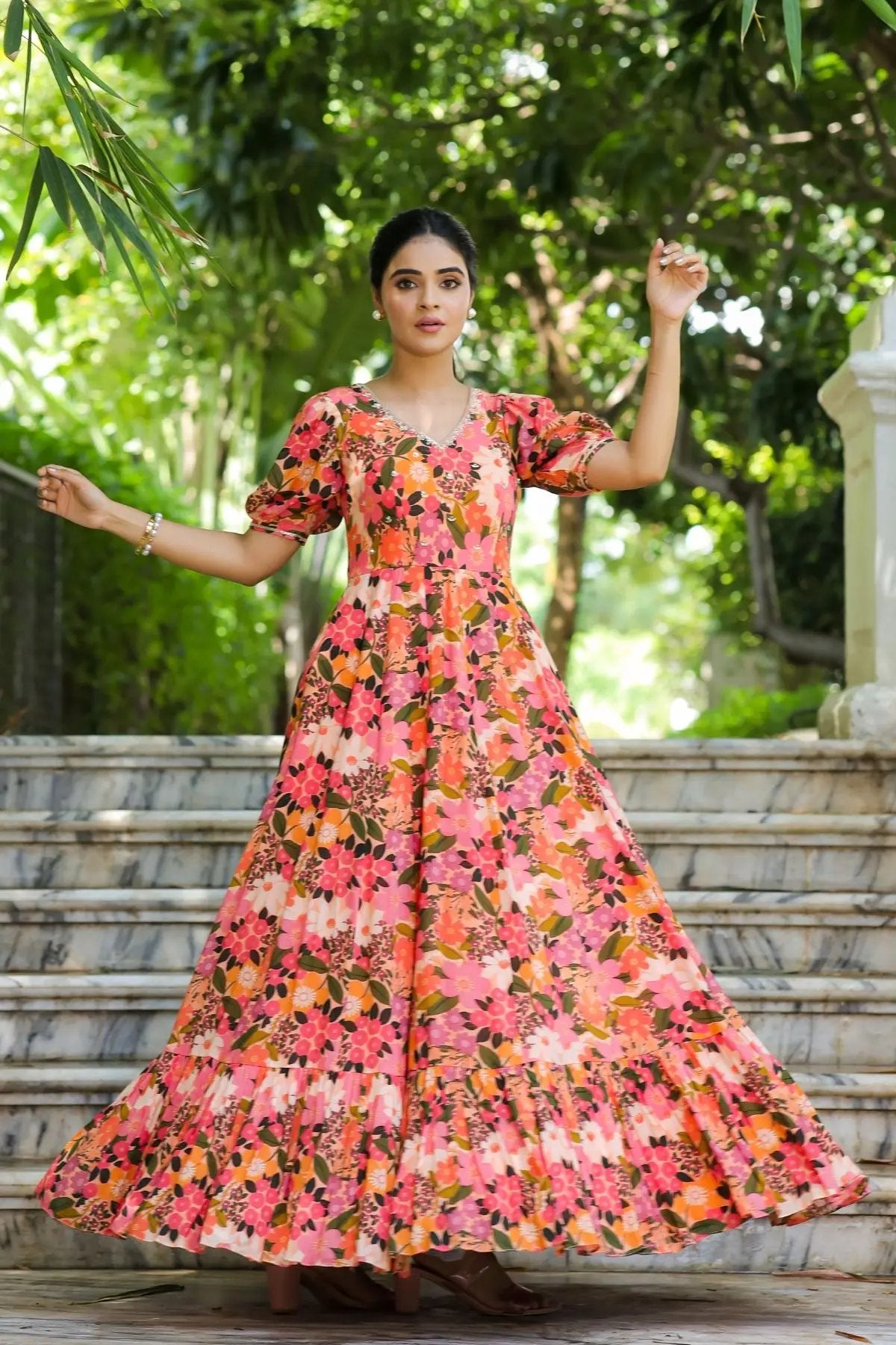 Model twirling in the Gulmohar Maxi Dress in Peach, showcasing its voluminous skirt, floral print, and exquisite ethnic charm.