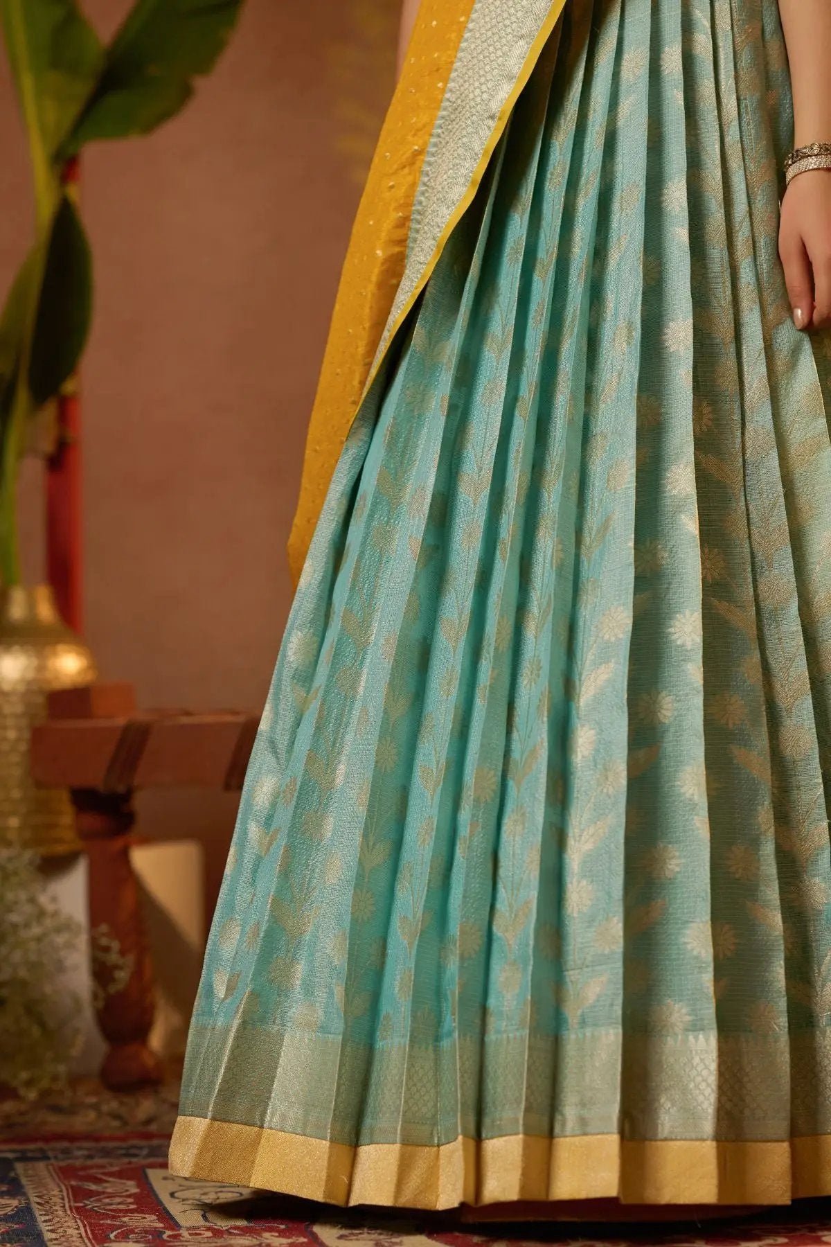 Detailed view of the blue pleated skirt with golden motifs from the Aadhya Lehenga Set in Yellow. Traditional elegance at bullionknot.