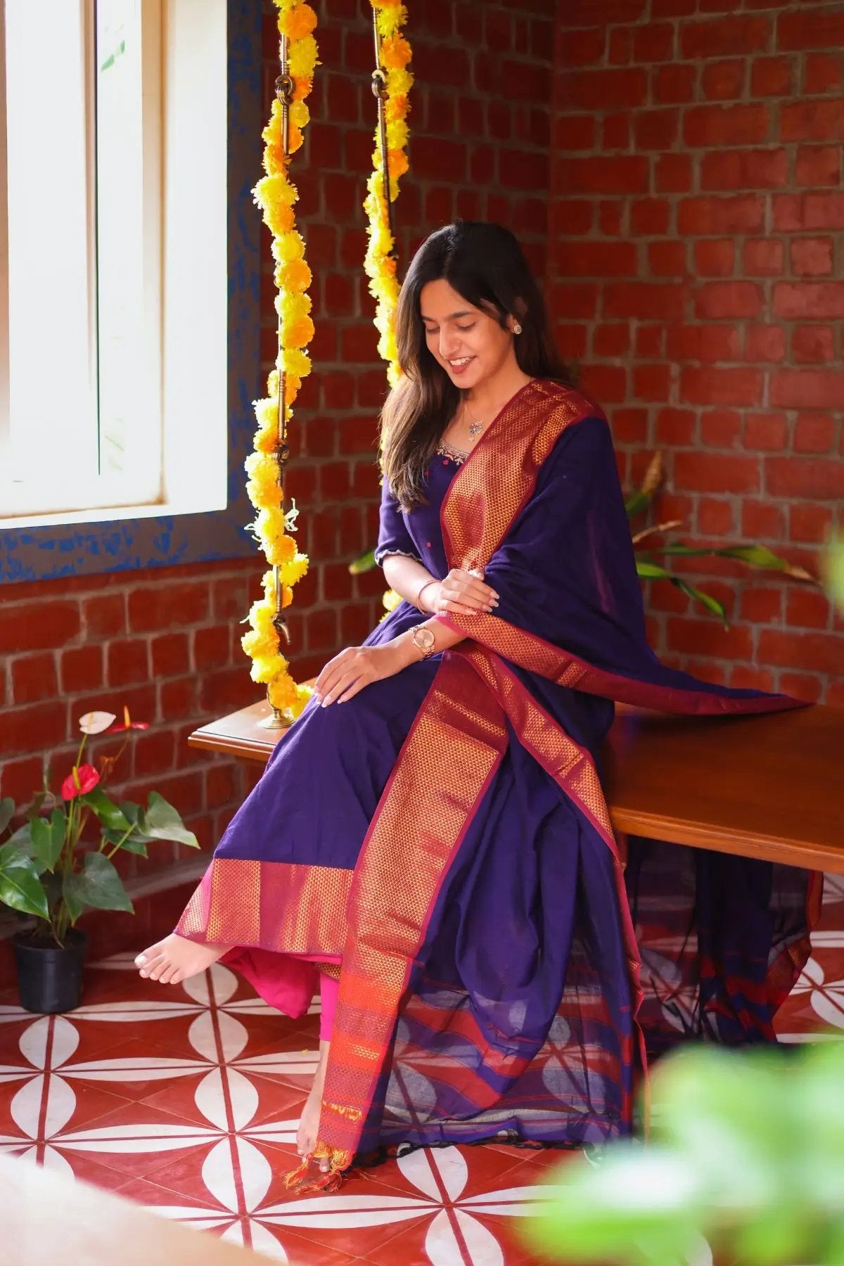 Seated woman in Meghna Anarkali dress, purple and gold