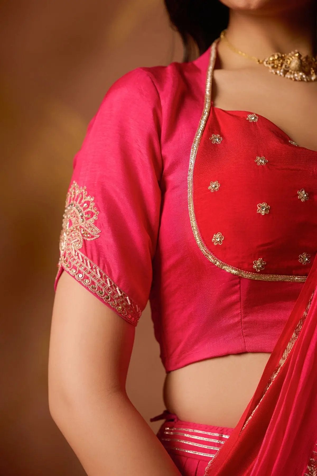 Close-up of the Pritti Lehenga Set blouse in Rani Pink, showcasing delicate embroidery and elegant gold detailing for a regal touch.