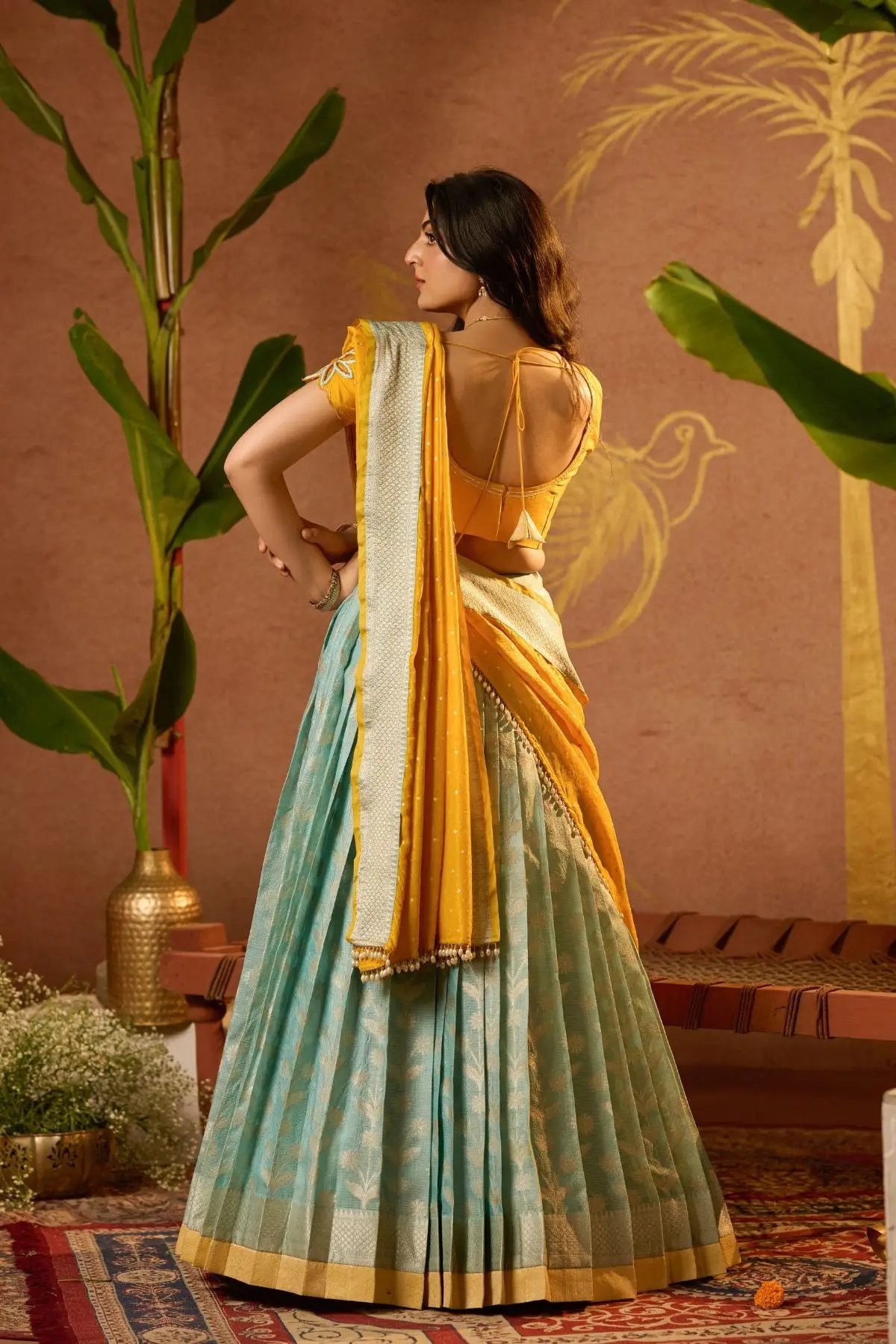 Back view of Aadhya Lehenga Set in Yellow showcasing the elegant blouse design and flowing dupatta. Traditional wear at bullionknot.