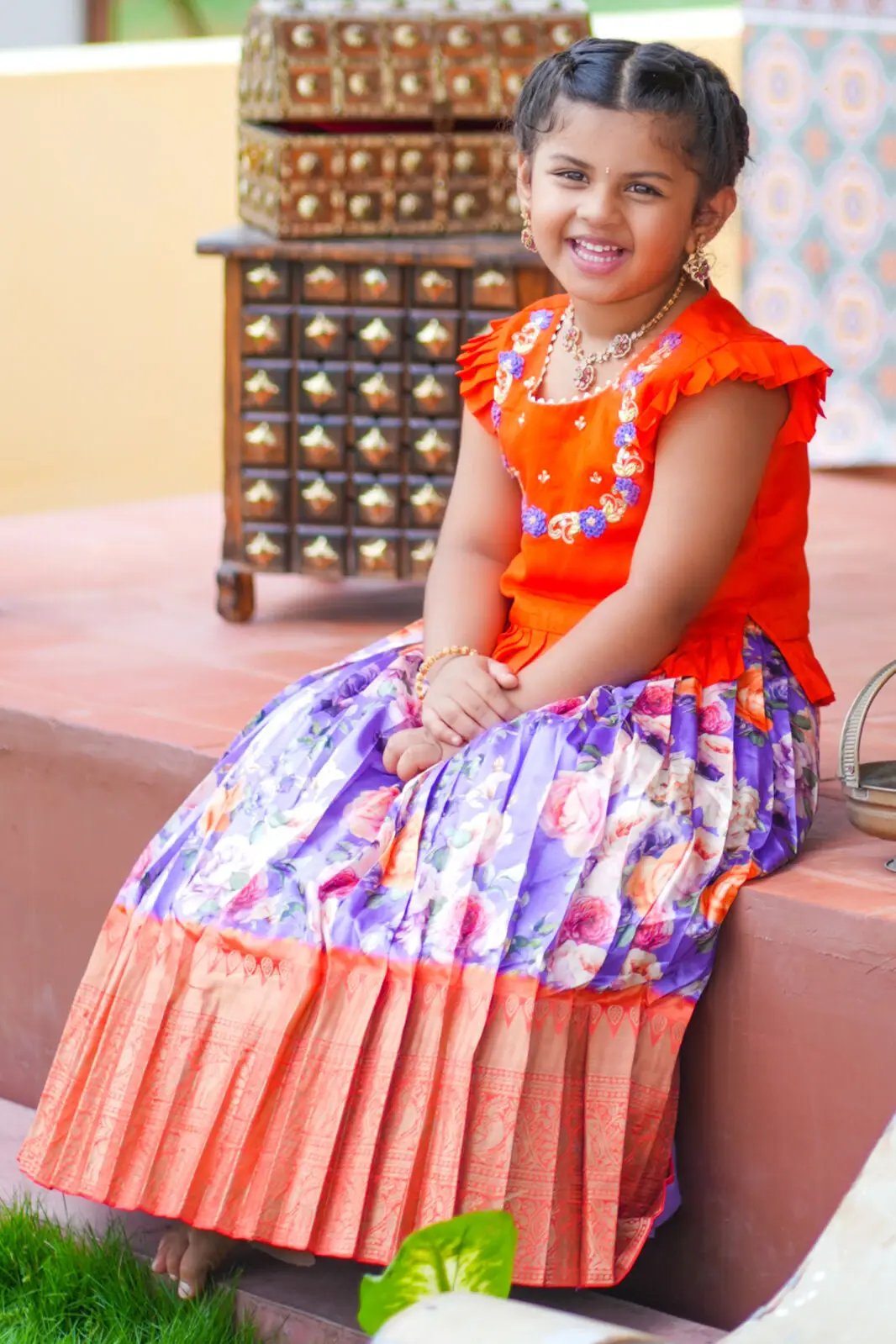 Seated child in Baby Blush Lehenga Set, purple floral design