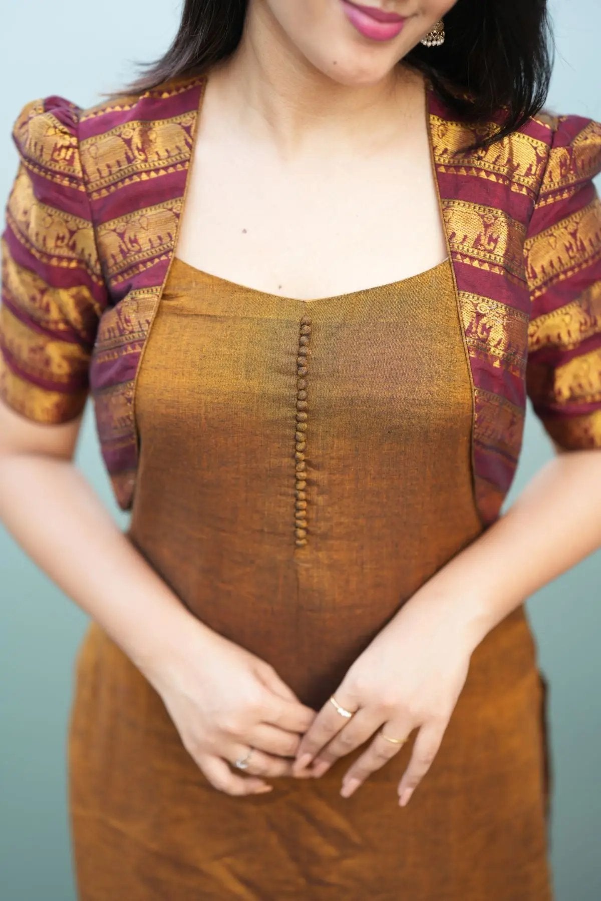 Close-up of the Barkha Kurta Set in ochre yellow, showcasing detailed maroon and gold patterned sleeves and buttoned neckline design.