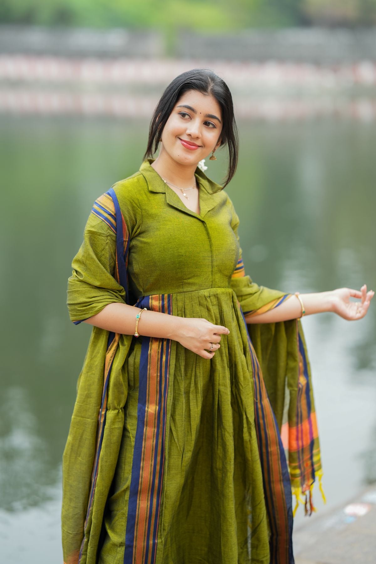 Elegant olive green Syahi Handloom Suit Set with a collared neckline and pleated design, paired with a striped dupatta. Shop this exclusive set at bullionknot.