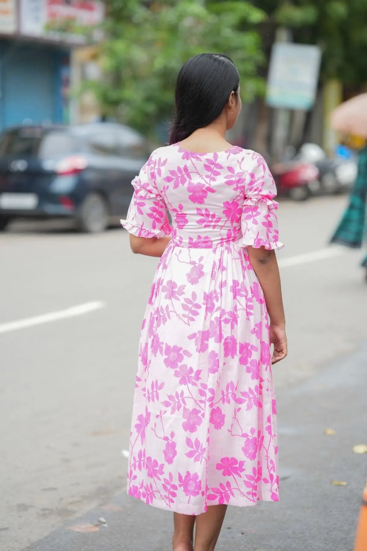 Back view of the Polly Midi Dress in pink, showcasing the floral print and flowy design with puffed sleeves.