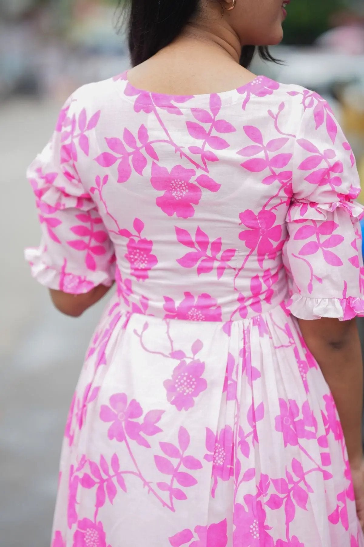 Close-up of the back of the Polly Midi Dress in pink, highlighting the floral pattern and ruffled sleeve details.