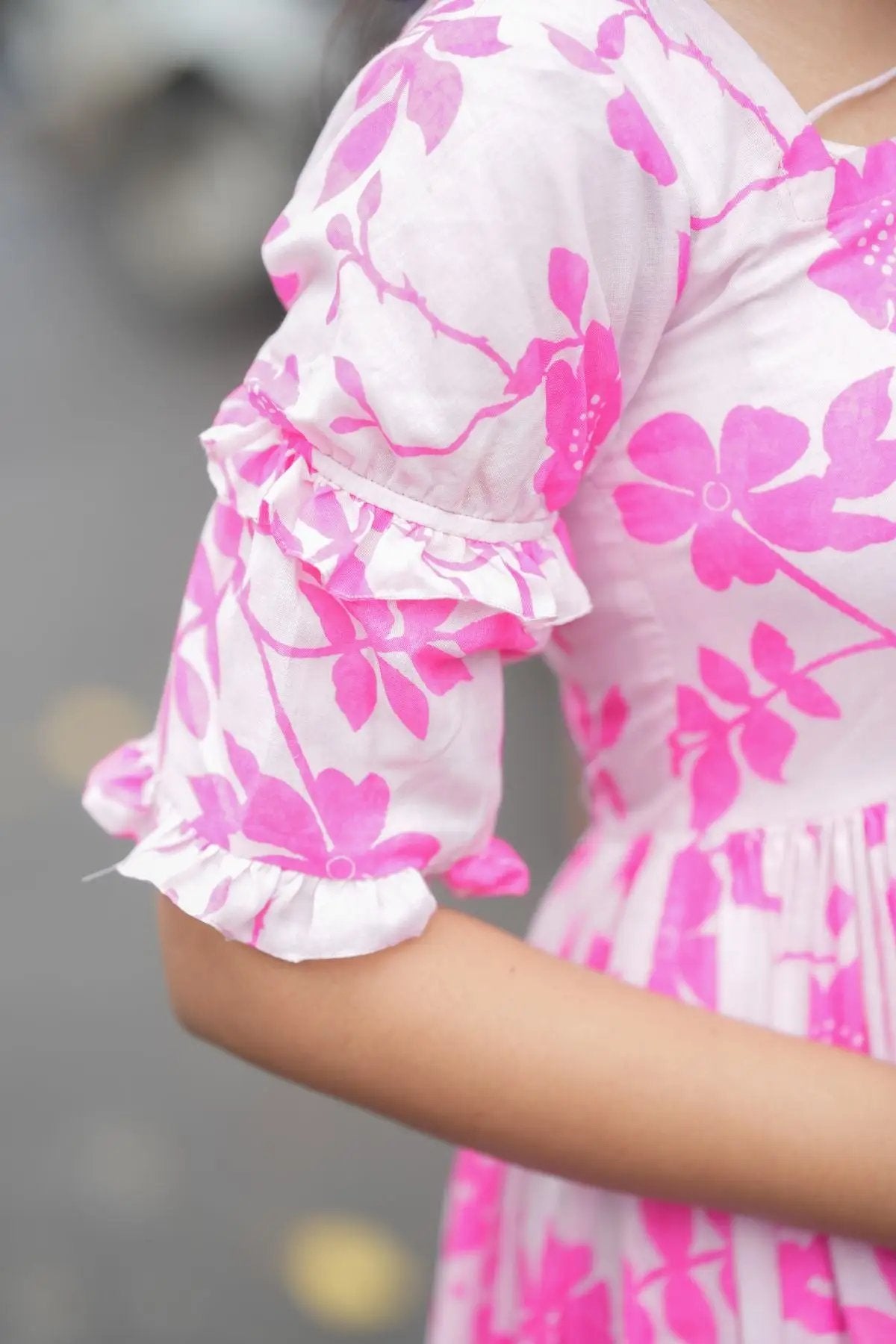 Close-up of the Polly Midi Dress in pink, highlighting the floral print and ruffled detailing on the puffed sleeves.