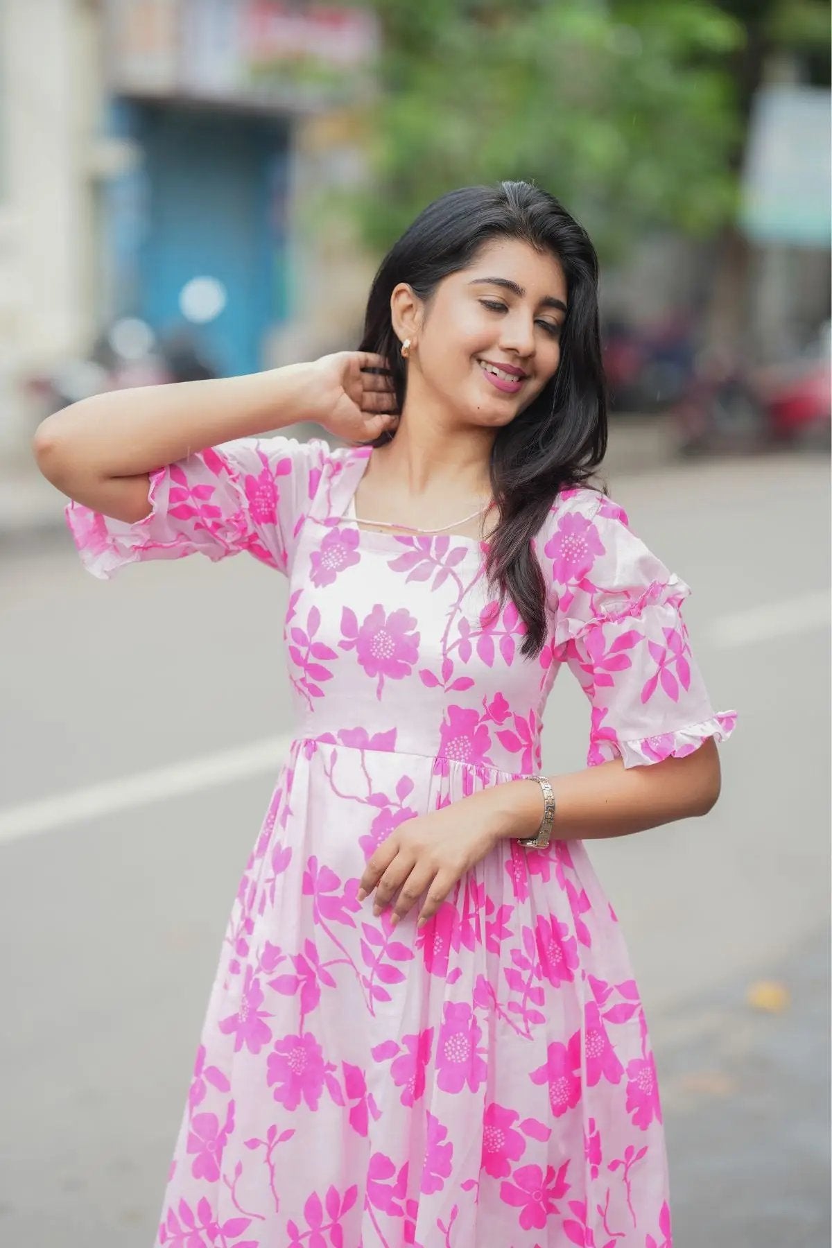 Model posing in the Polly Midi Dress in pink, emphasizing its floral design, square neckline, and feminine style.