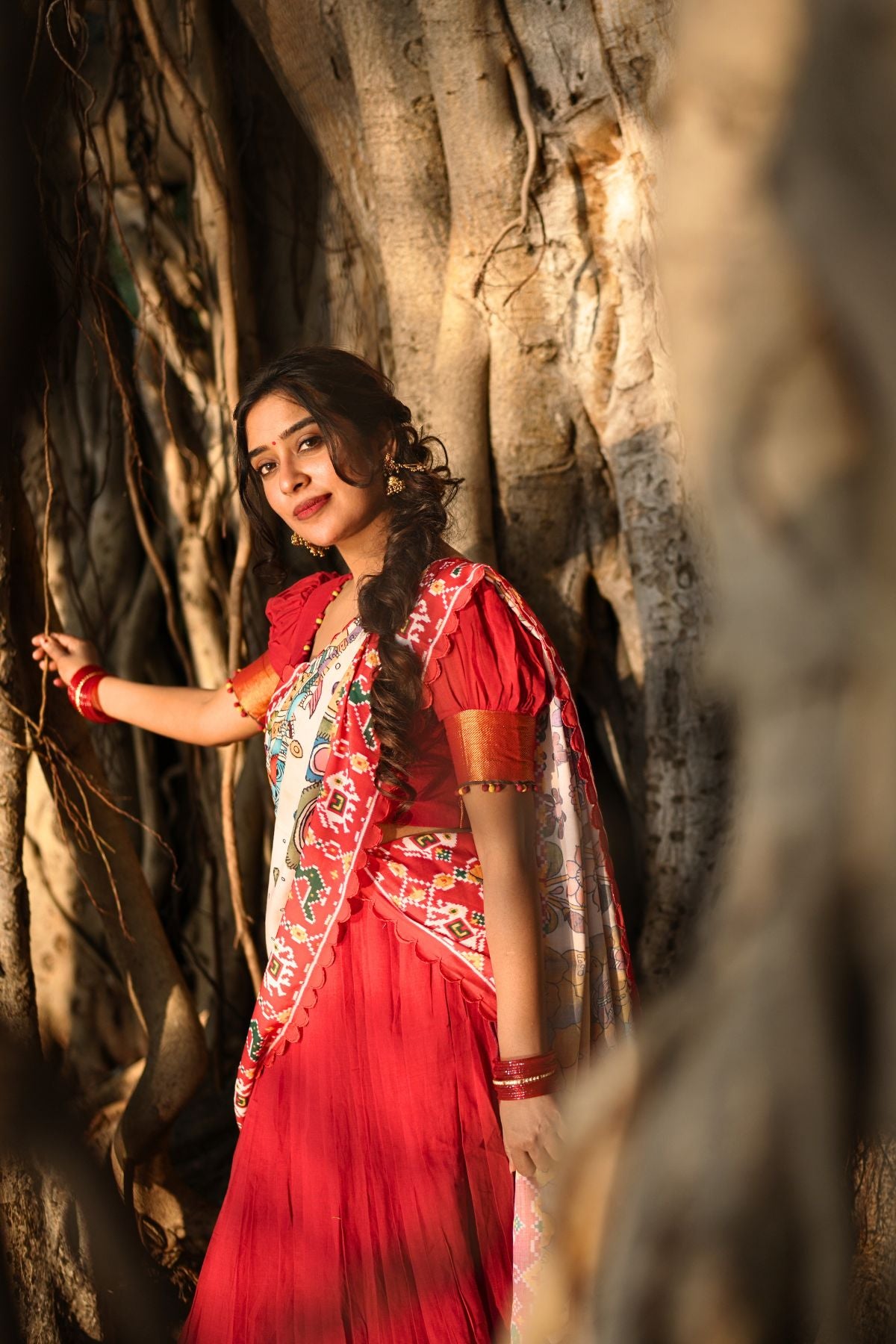 Exclusive Revti Handloom Lehenga Set in Red featuring a traditional design paired with a colorful dupatta, captured in a natural forest setting.