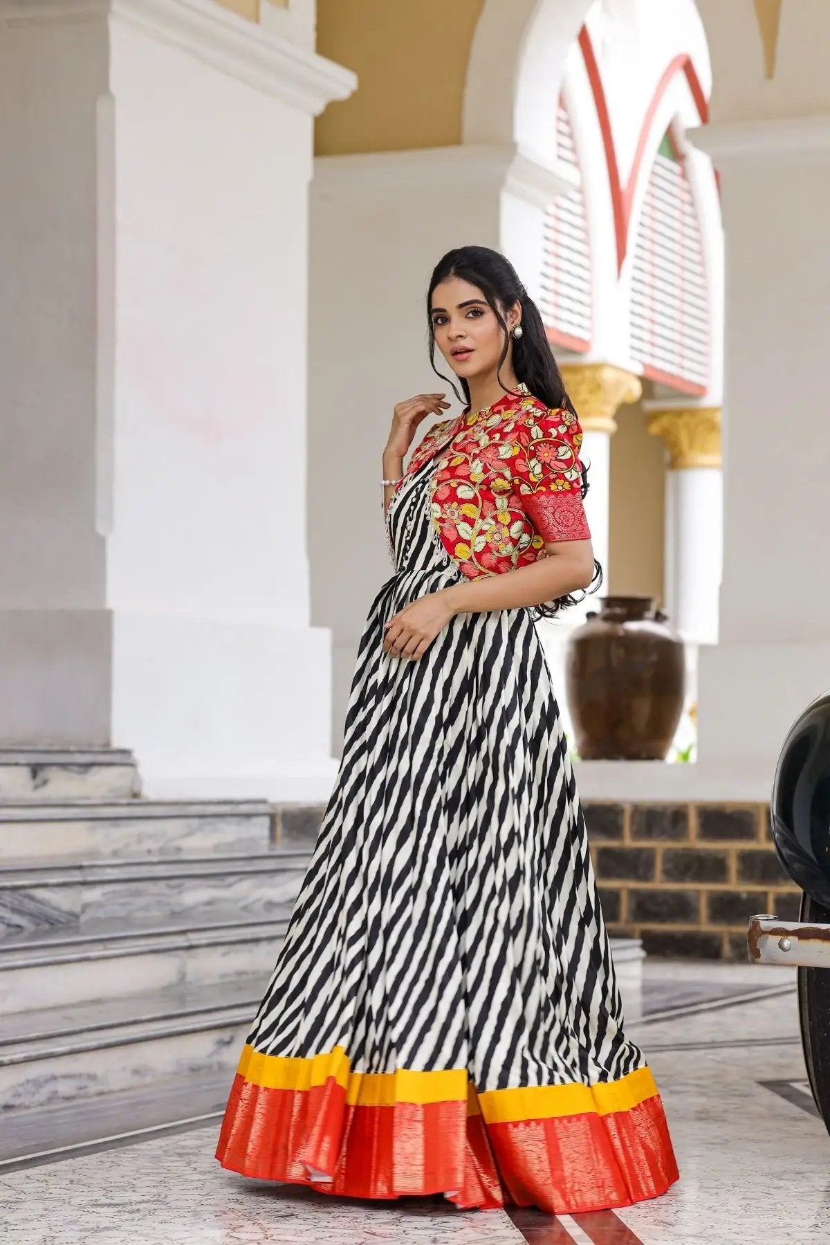 Rohini Kalamkari Jacket Dress in black with vibrant red floral jacket, striped black-and-white skirt, and orange-yellow border, perfect for ethnic occasions.