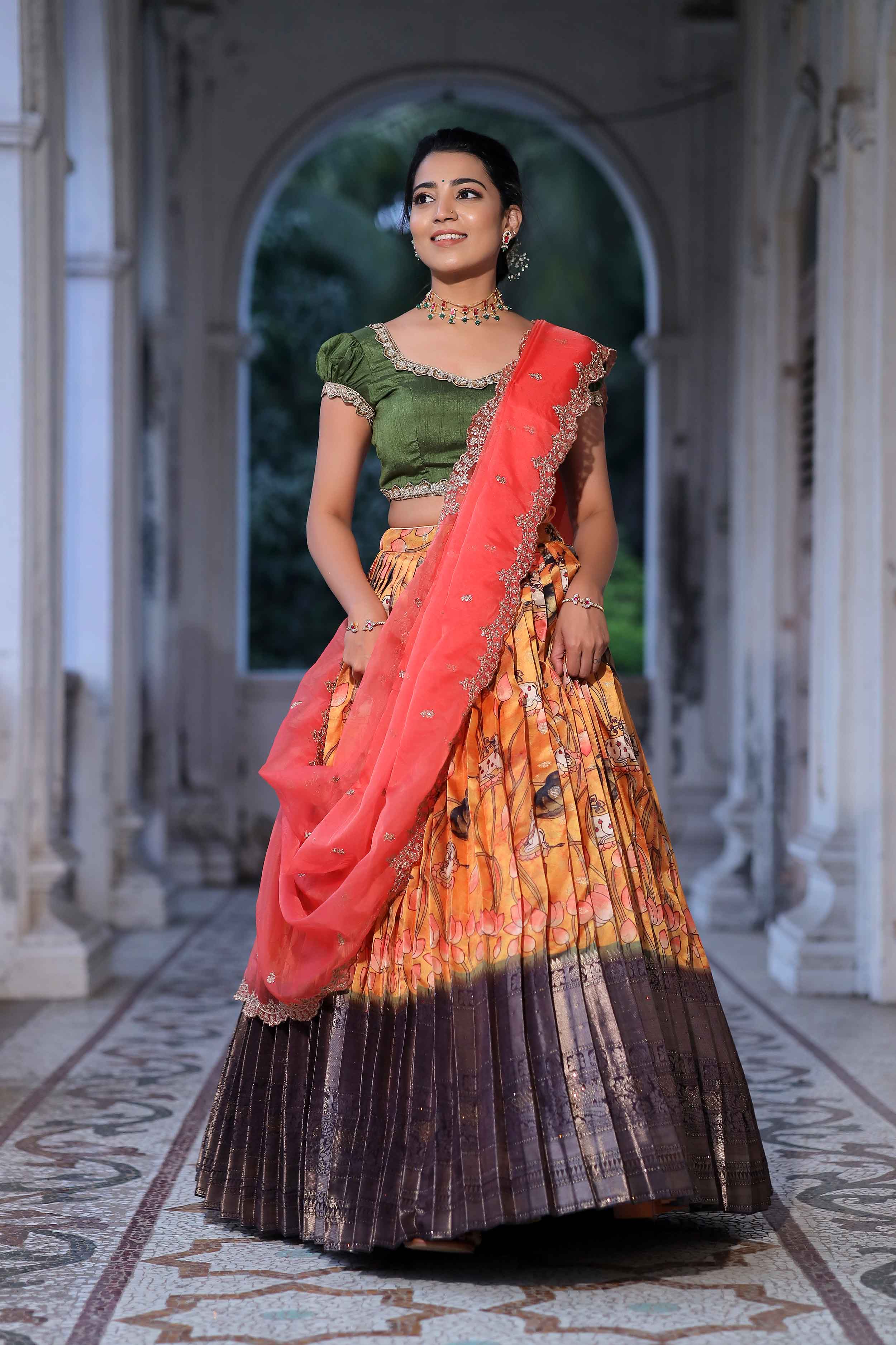 a woman in green and orange half saree