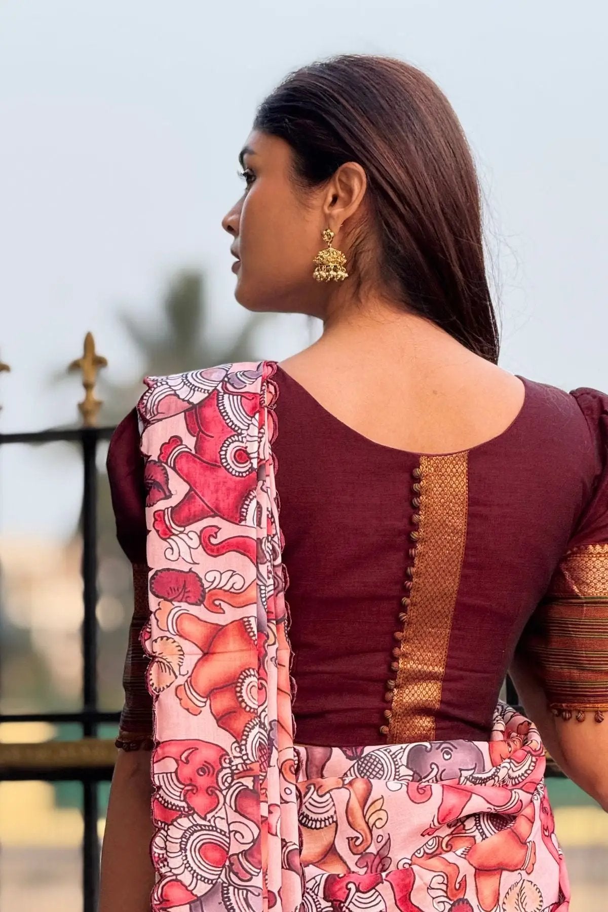 Rear close-up of Saumya Handloom Lehenga Set in maroon showcasing the blouse's textured design and vibrant floral dupatta.