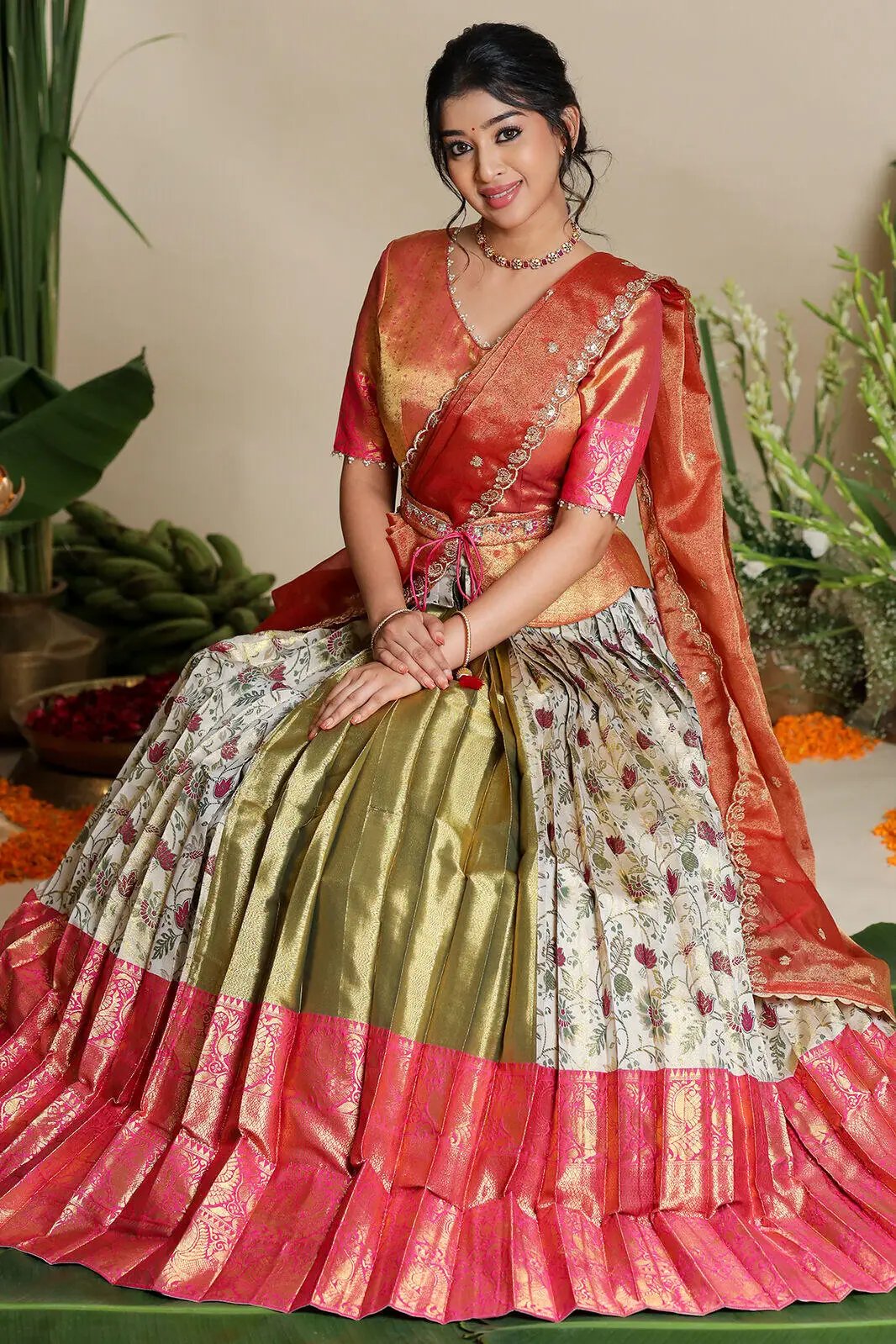 Model seated in ivory and pink half saree lehenga