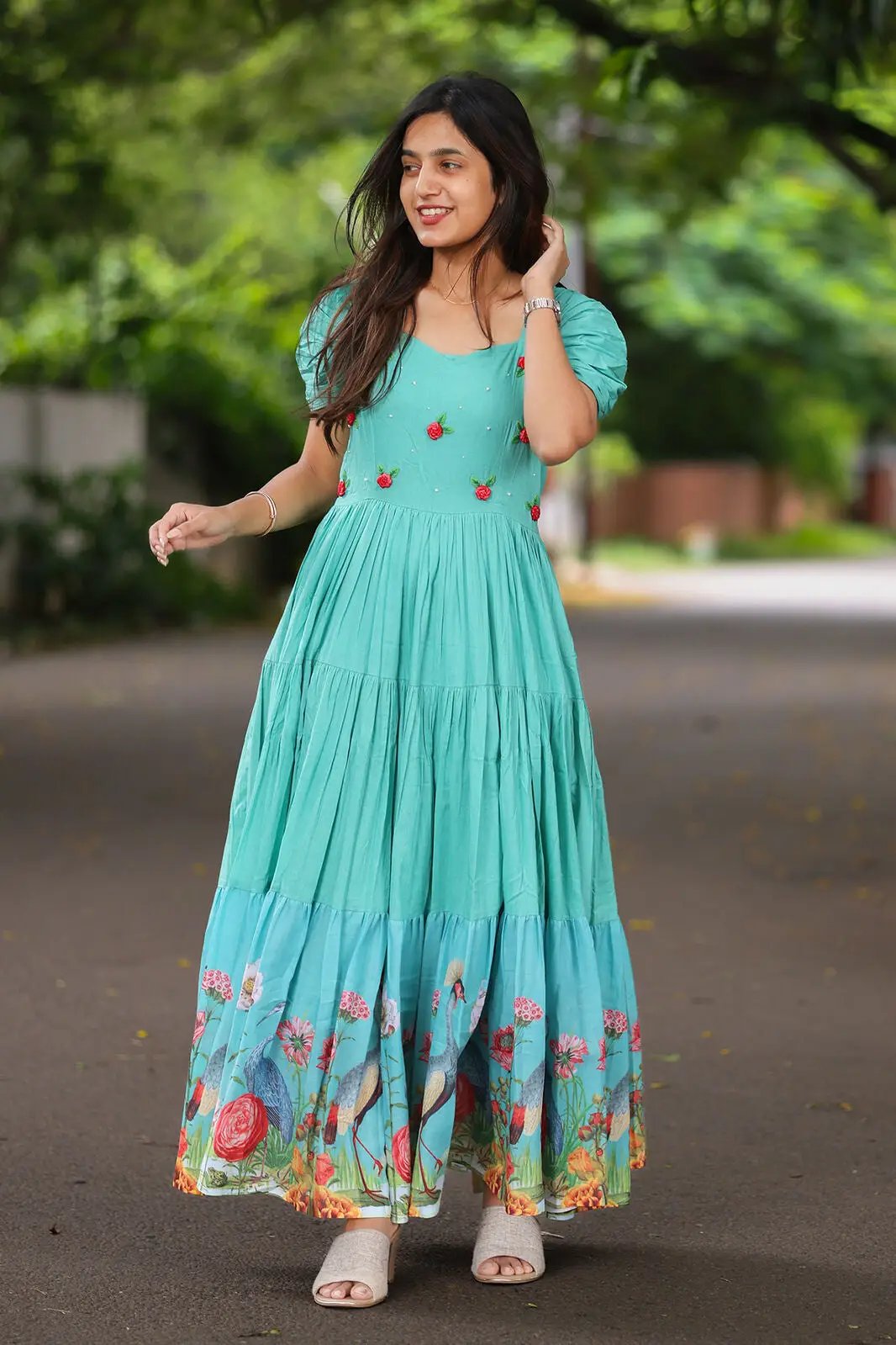 Woman in aqua dress with floral hem, walking outdoors.