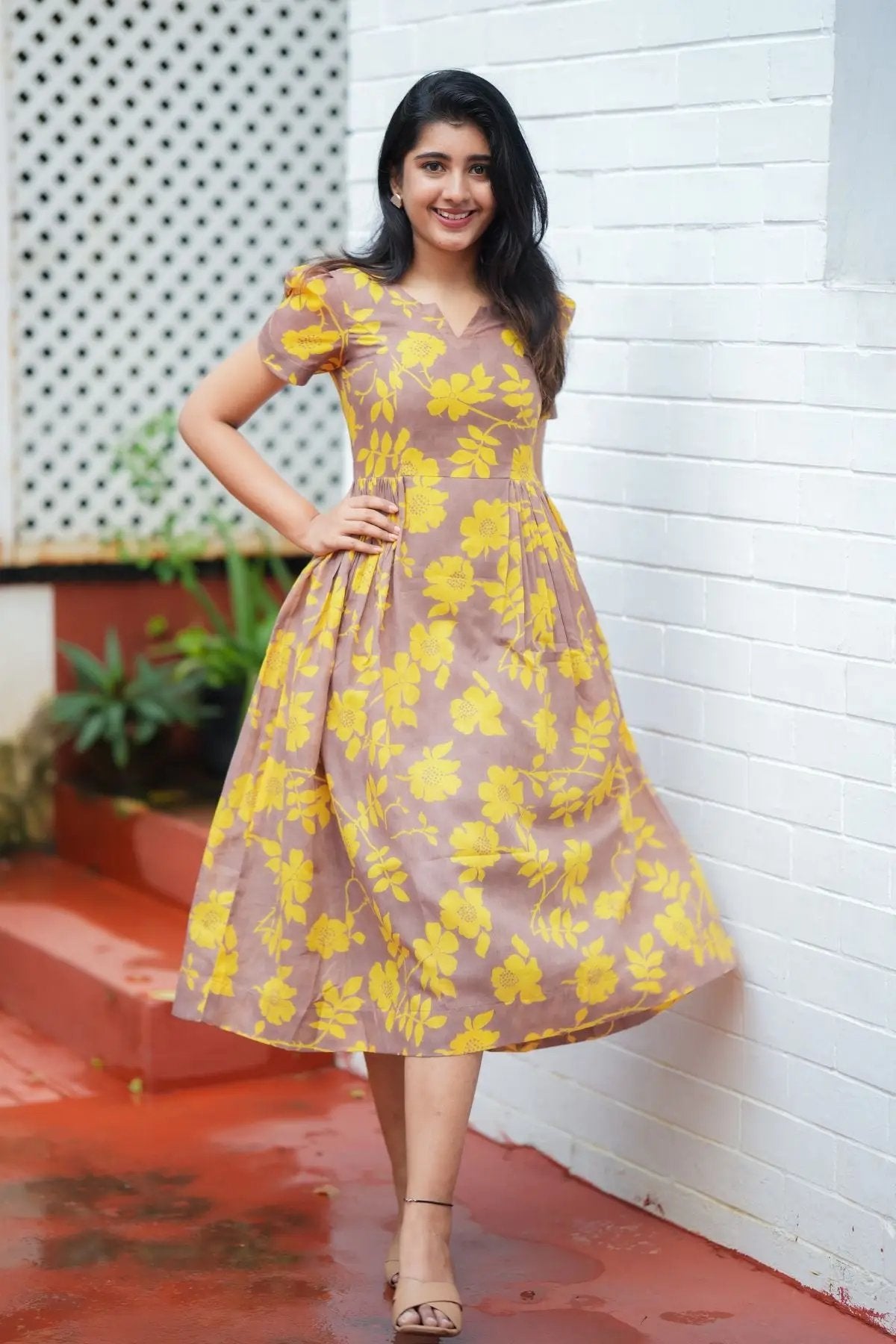 Full-length view of Yelena Midi Dress with yellow floral patterns, showcasing its flowy design and summer appeal.