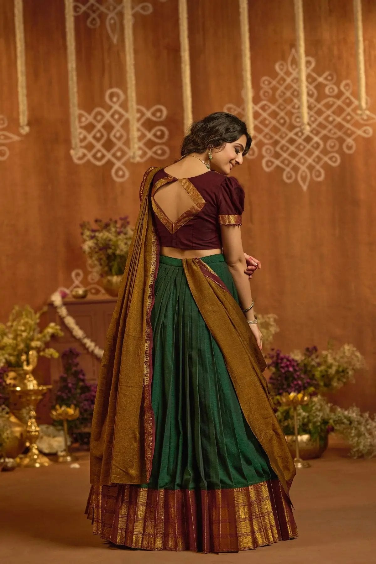 Back view of Devara Handloom Lehenga Set in Green showcasing maroon blouse with cut-out design and gold-bordered pleats.