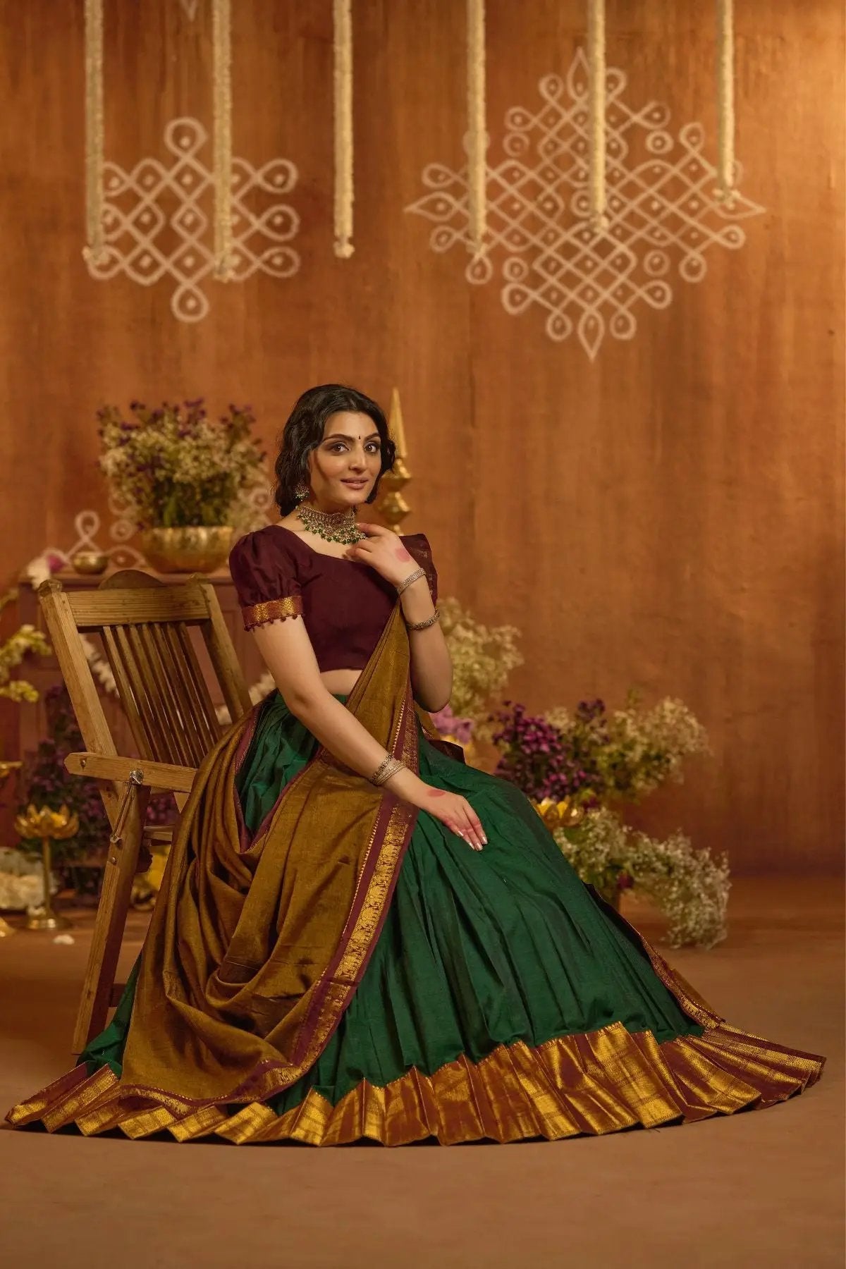 Seated view of Devara Handloom Lehenga Set in Green with maroon blouse, gold border, and pleated design, perfect for festive wear.