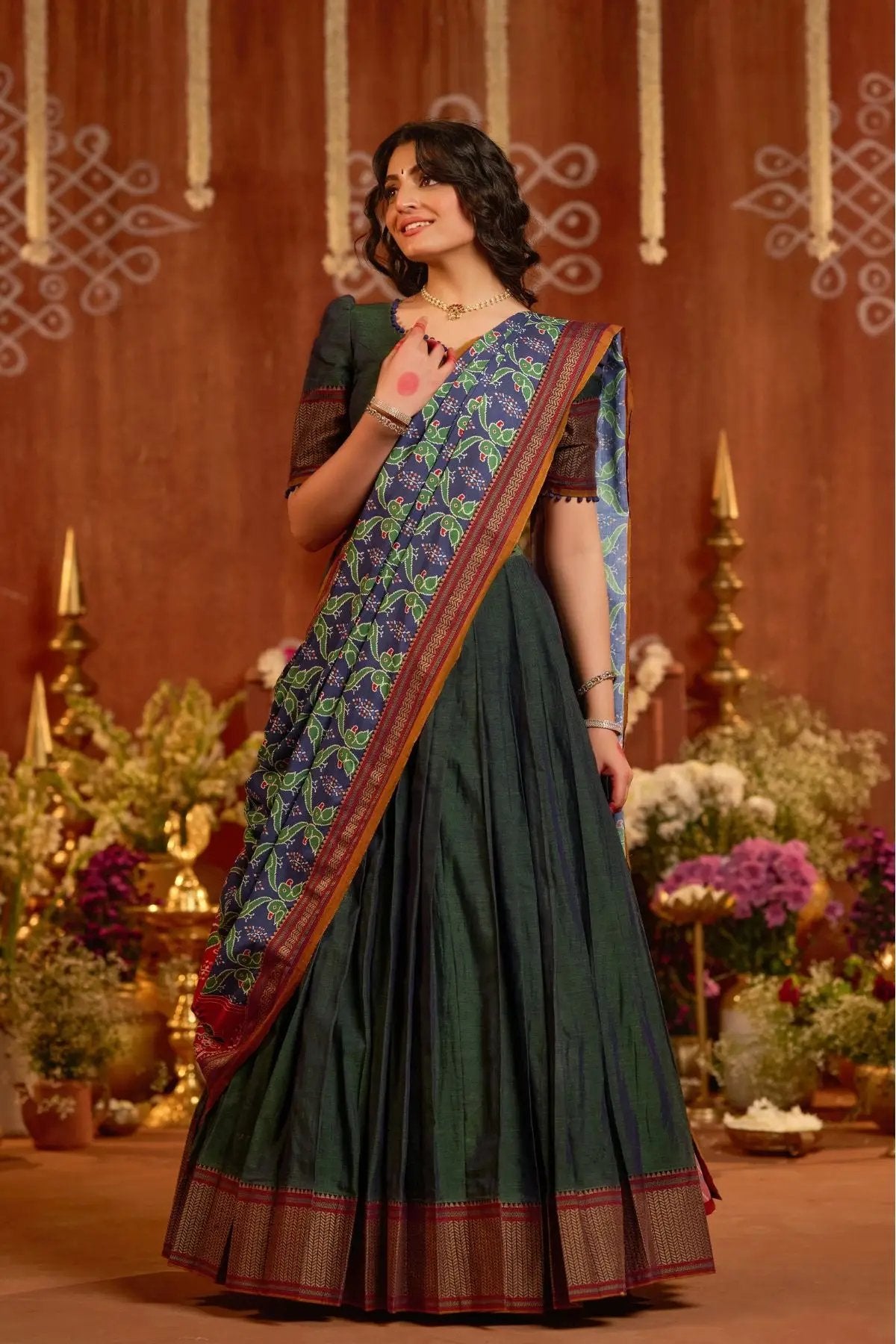 Model wearing Dhiwija Handloom Lehenga Set in peacock green with a colorful dupatta, perfect for traditional and ceremonial occasions.