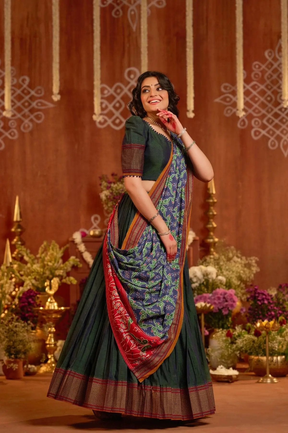 Dhiwija Handloom Lehenga Set in peacock green with a vibrant dupatta, styled in a festive backdrop with floral and golden decor.