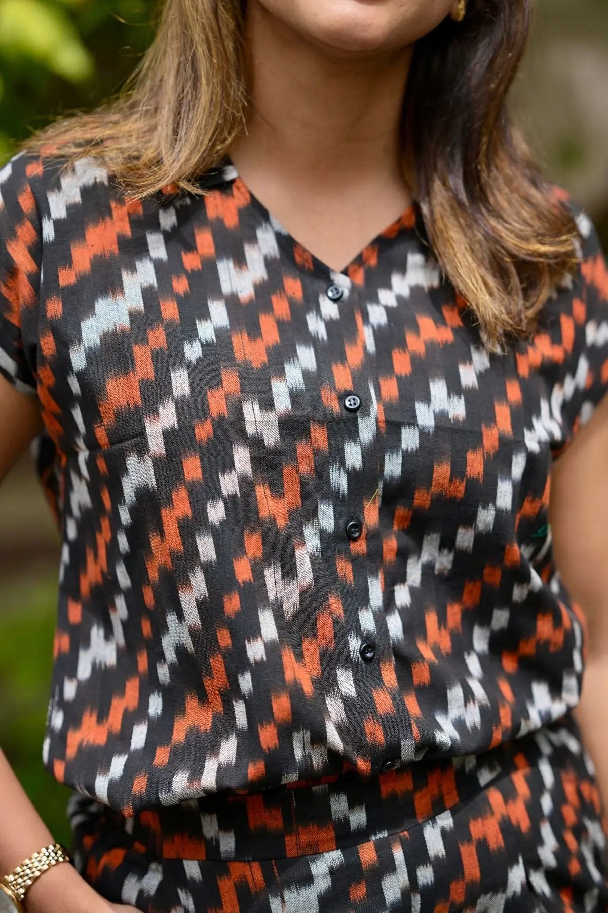 Close-up of patterned black and orange buttoned top